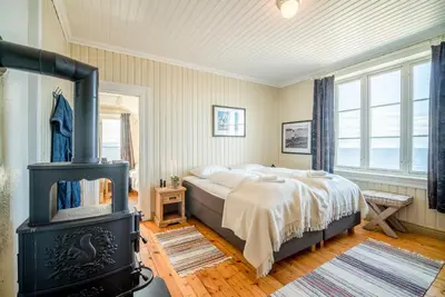 a bedroom with a bed and a wood stove at Flatflesa Fyr - by Classic Norway Hotels in Rindarøy