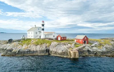 a lighthouse on an island in the water at Flatflesa Fyr - by Classic Norway Hotels in Rindarøy