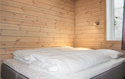 a white bed in a wooden room with a window at Privat'n in Hemsedal