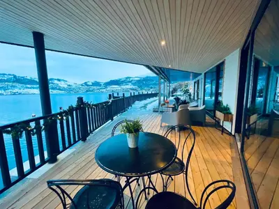 a balcony with a table and chairs and the water at Panoramaresort in Hardangerfjorden leilighet i sjøkanten ved Hardangerfjorden for 7 personer boat , sauna,kajak, SUP for rent in Øystese