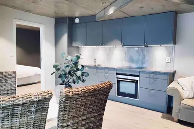 a kitchen with blue cabinets and wicker chairs at Panoramaresort in Hardangerfjorden leilighet i sjøkanten ved Hardangerfjorden for 7 personer boat , sauna,kajak, SUP for rent in Øystese