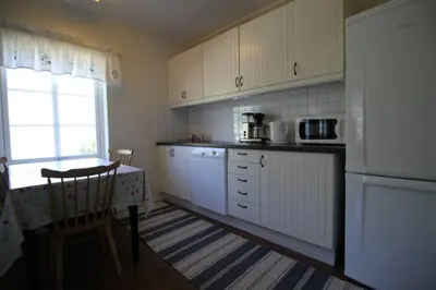 a kitchen with a table and a white refrigerator at Bellahuset in Sæbø