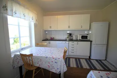a kitchen with a table and a white refrigerator at Bellahuset in Sæbø
