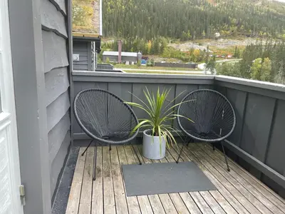 a balcony with two chairs and a potted plant at Tinden in Hemsedal