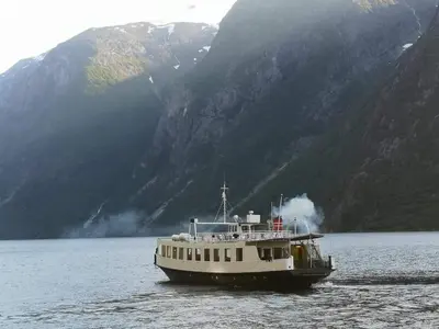 a boat on the water in front of a mountain at Iris Vedal in Nauste