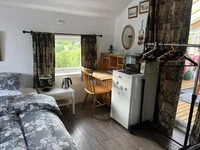 a bedroom with a bed and a kitchen with a table at Iris Vedal in Nauste
