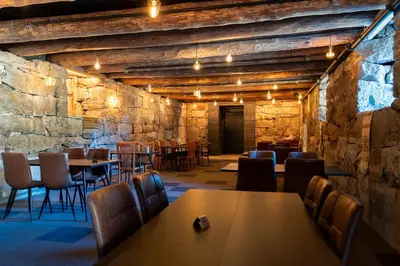 a restaurant with tables and chairs and a stone wall at Jølstraholmen Landskapshotell in Vassenden