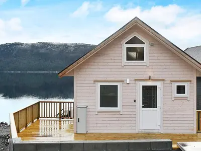 a house with a deck next to a lake at 8 person holiday home in VATNE in Vatne