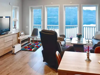 a living room with a couch and a tv and some chairs at 8 person holiday home in VATNE in Vatne