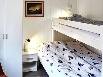 a bedroom with a bunk bed with blue and white sheets at 8 person holiday home in VATNE in Vatne