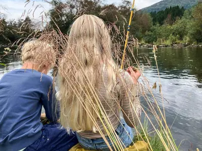 two people sitting in a boat in the water at Secluded Mountain Retreat-By Traum in Vassenden