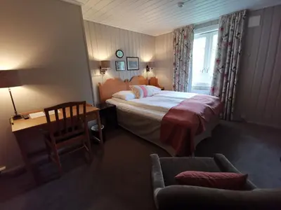 a bedroom with a bed and a desk and a chair at Sanner Hotell in Gran