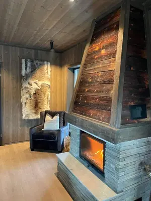a living room with a fireplace and a chair at Fjelleventyret gårdsovernatting in Skjåk