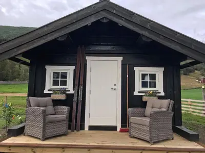 a black shed with two chairs on a wooden deck at Fjelleventyret gårdsovernatting in Skjåk