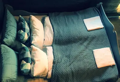 a bed with white pillows and a green blanket at Fjelleventyret gårdsovernatting in Skjåk