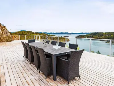 a table and chairs on a deck with a view of the water at 12 person holiday home in Fitjar in Fitjar