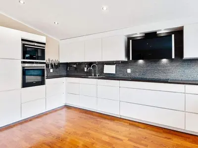 a kitchen with white cabinets and a wooden floor at 12 person holiday home in Fitjar in Fitjar