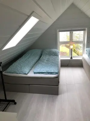 a bed in a attic room with a window at Tunold Gård - Freden in Stryn