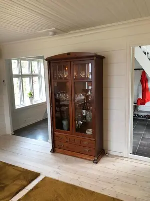 a wooden cabinet with glass doors in a room at Tunold Gård - Freden in Stryn