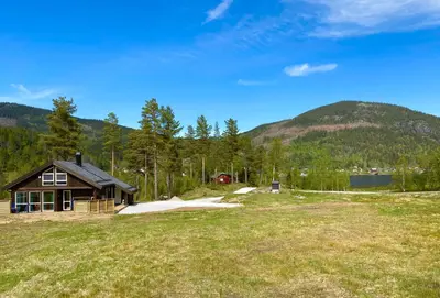 a house in a field next to a mountain at Tuddal Hyttegrend HYTTA KÅNS in Tuddal
