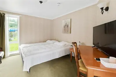 a bedroom with a bed and a desk and a television at Aursnes Hotell in Sykkylven