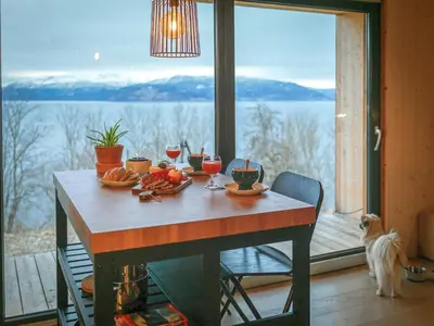 a table with food and drinks and a dog looking out a window at Hardanger Fjordtun PANORAMA cabin near the Hardangerfjord with fantastic fjordview, silence and nature in Herand