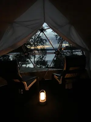 two chairs and a light in a tent with a window at FUGELVÅGEN, cabins and glamping in Ålvundfjord