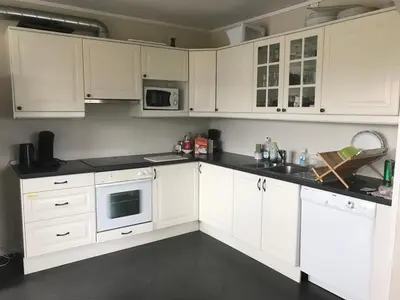 a kitchen with white cabinets and black counter tops at EIDE Gjestehus in Eide