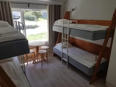 a room with two bunk beds and a table and stool at Folgefonn Gjestetun in Jondal