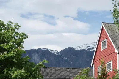 a red house with snow covered mountains in the background at Olden Panorama Apartments - Fjord view - High Standard in Olden