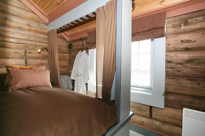 a bedroom with wooden walls and a bed with a window at Korsholmen - by Classic Norway Hotels in Karvåg