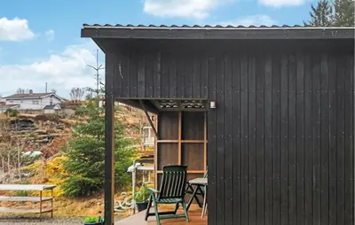 a black shed with a chair and a table at Amazing Apartment In Fjell in Lokøy