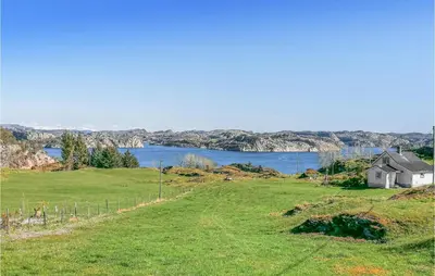 a house in a field next to a body of water at Amazing Apartment In Fjell in Lokøy