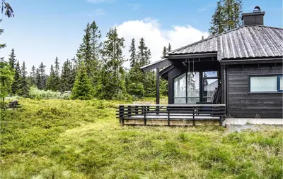 a cabin in a field with trees in the background at Stunning Home In Sjusjøen With Sauna in Sjusjøen