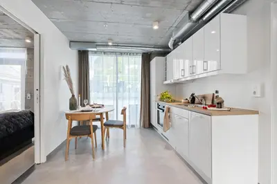 a kitchen with white cabinets and a table and chairs at Aalesund City Apartment in Ålesund