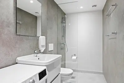 a bathroom with a sink and a toilet and a mirror at Aalesund City Apartment in Ålesund