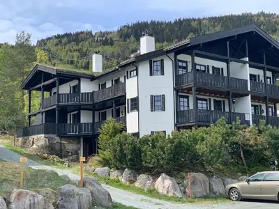 a large white building with a car parked in front of it at Norefri apartment with sauna at Nedre Norefjell Ski In- Ski Out in Noresund