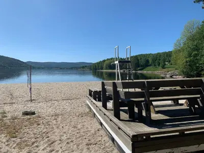 a bench on a beach next to a body of water at Norefri apartment with sauna at Nedre Norefjell Ski In- Ski Out in Noresund
