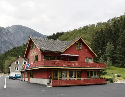 a large red building in a parking lot at Kvamsdal Pensjonat 3 in Eidfjord