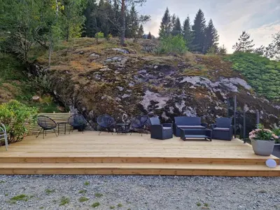 a wooden deck with chairs and chairs on top of a hill at Kvamsdal Pensjonat 3 in Eidfjord
