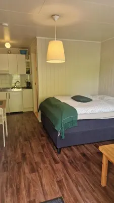 a bedroom with a large bed and a kitchen at Kvamsdal Pensjonat 3 in Eidfjord
