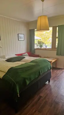 a bedroom with a large bed with a green blanket at Kvamsdal Pensjonat 3 in Eidfjord
