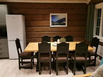 a dining room with a table and chairs and a refrigerator at STORHAUGEN GARD in Lom