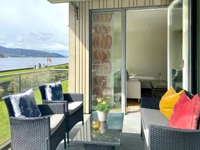 a patio with chairs and a table with a view of the water at Cityfjord apartment in Bergen centrum in Bergen