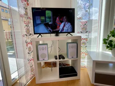 a tv on top of a white stand with speakers at Cityfjord apartment in Bergen centrum in Bergen