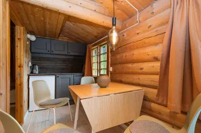 a dining room in a log cabin with a table and chairs at Ljoshaugen Camping in Dombås