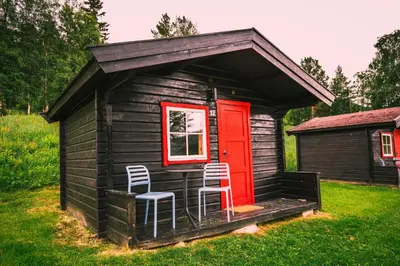 a small cabin with two chairs and a red door at Ljoshaugen Camping in Dombås