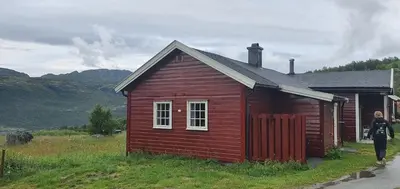 a woman standing in front of a red house at Midtgard in Tyinkrysset
