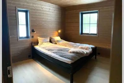 a small bed in a room with two windows at Hytte i Stryn med elbil lader in Stryn