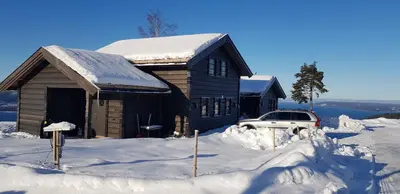 a building covered in snow with a car parked in front at Mjøshytte in Stange